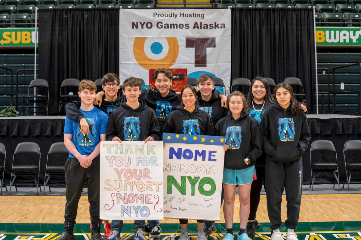 Young sports team posing for photo with two large signs