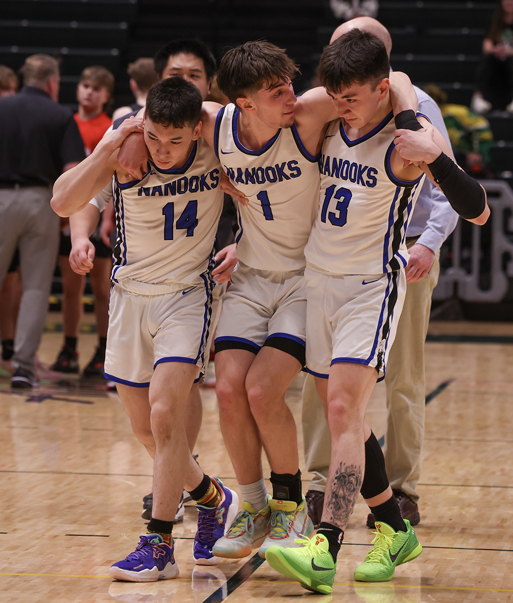 Nanooks Ethan Hannon (No. 14) and Jade Greene (No. 13) assist Finn Gregg (No. 1) off the court late in the game after he developed cramps.
