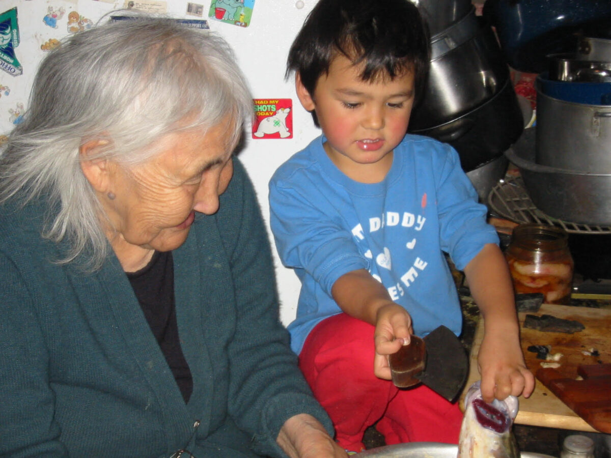 A young Sam Schimmel learns the use of an ulu with his great-grandmother Estelle Oozevaseuk (Penapak). Oozevaseuk, who passed away in 2013, was a renowned speaker of the St. Lawrence Island Yupik language. Photo courtesy Jeremy Schimmel.