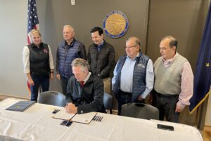 Gov. Mike Dunleavy signs Senate Bill 98 on Friday, June 23, as Reps. Delena Johnson, Bryce Edgmon, Neal Foster, and Sens. Lyman Hoffman and Donny Olson watch. Photo by Greg Knight/KNOM