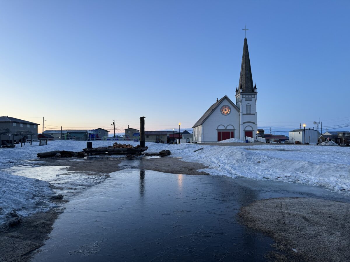 The Iditarod Trail's famous Burled Arch rests in pieces scattered across the ground with Old St. Joes Church in the background. One of the pillars of the arch lays on the ground. Ben Townsend photo.
