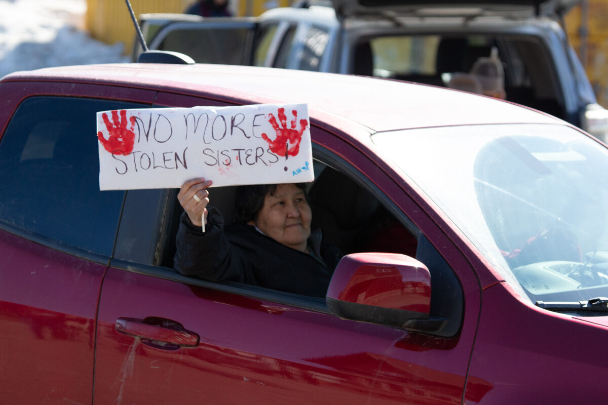 A passenger of a car holds a sign saying "No more stolen sisters" out of the window. Ben Townsend photo.